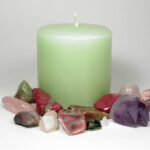 A green apple aromatherapy candle surrounded by natural stones which can be used in crystal healing.