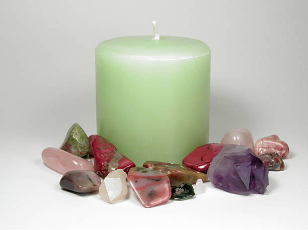 A green apple aromatherapy candle surrounded by natural stones which can be used in crystal healing.